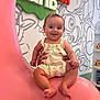 Leya participe au concours pour gagner de l'argent avec cette photo : baby, child, smiling, pink_chair, floral_outfit, hands, cartoon_wall_art, nickelodeon_sign, indoor, cute, sitting, happy, person, infant, playful, colorful, headband, footwear_free, toy_shelf, background