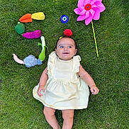 Leya a rejoint le concours — aidez-le/la à gagner de superbes lots ! baby, child, grass, outdoor, dress, plush_toys, vegetables, pinwheel, greenery, smiling, barefoot, playful, toy, summer, happy, nature, lying_down, colorful, cute, fun