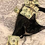 cat, black_cat, money, dollar_bills, bedspread, patterned_bedspread, lying_down, whiskers, relaxing, indoor, currency, feline, pet, animal, domestic_cat, sleepy, black_and_white, cash, resting, cozy