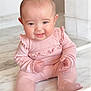 baby, infant, pink_clothing, sitting, marble_floor, smiling, cute, portrait, child, indoors, lace, happy, young_child, one_person, head, face, hand, footwear, soft_lighting, cheeks