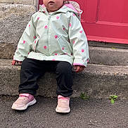 Nairobi-Louise is registered to the contest to win money with this photo: casual_clothing, casual_pose, child, curious_expression, curly_hair, cute, daylight, outdoor, person, pink_shoes, portrait, raincoat, red_door, sidewalk, sitting, small_plant, stone_step, street, toddler, young_child