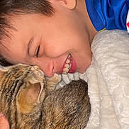 Medina participe au concours pour gagner de l'argent avec cette photo : boy, cat, tabby_cat, smiling, close_up, blanket, cozy, indoor, affection, friendship, cute, pet, child, happy, face, fur, resting, warm, comfort, young