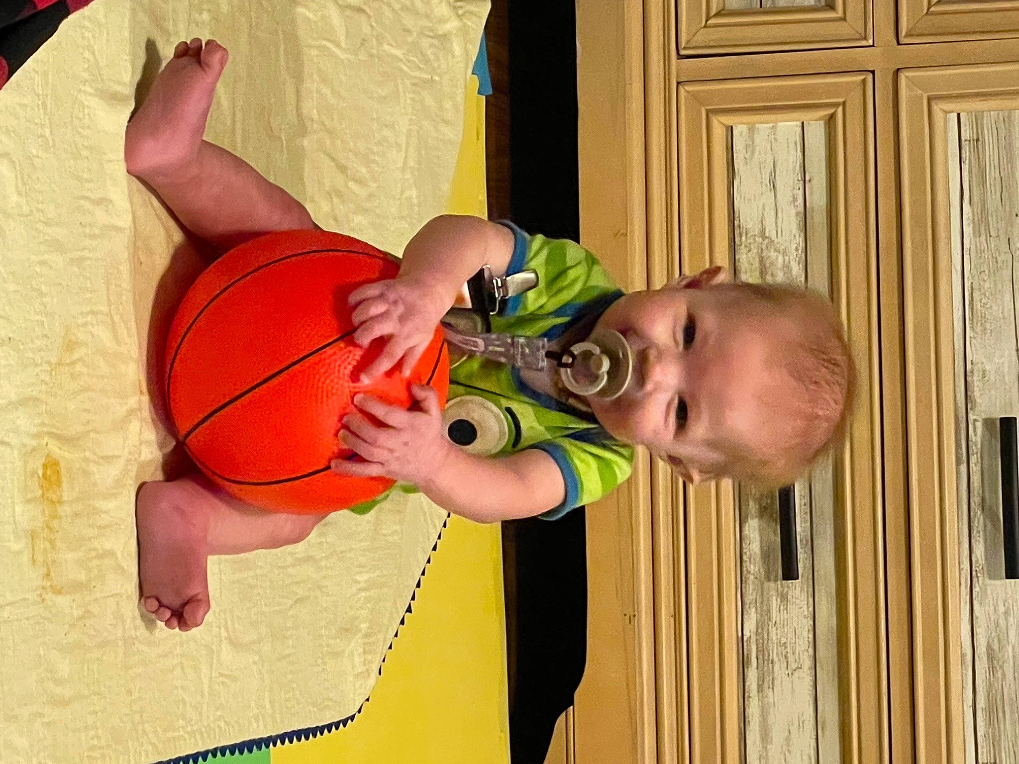 William is registered to the contest to win money with this photo: baby, baby_toddler_clothing, ball, basketball, child, elbow, fun, happy, joint, mammal, orange, person, product, shorts, sports_equipment, thumb, toddler, varnish, womens_basketball, wood