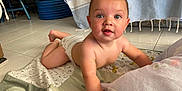 Thyliam a rejoint le concours — aidez-le/la à gagner de superbes lots ! baby, infant, diaper, quilt, floor, tile, indoor, blue_furniture, tablecloth, curious, child, person, crawling, cute, smiling, skin, arm, head, eyes, mouth