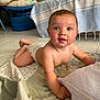 baby, infant, diaper, quilt, floor, tile, indoor, blue_furniture, tablecloth, curious, child, person, crawling, cute, smiling, skin, arm, head, eyes, mouth