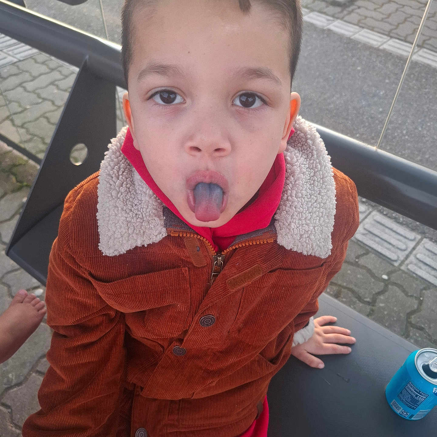 Nur participe au concours pour gagner de l'argent avec cette photo : barefoot, bench, boy, brown_jacket, bus_stop, casual_clothing, child, cute, daylight, expression, face, hand, outdoor, pavement, playful, portrait, red_pants, soda_can, tongue_out, young