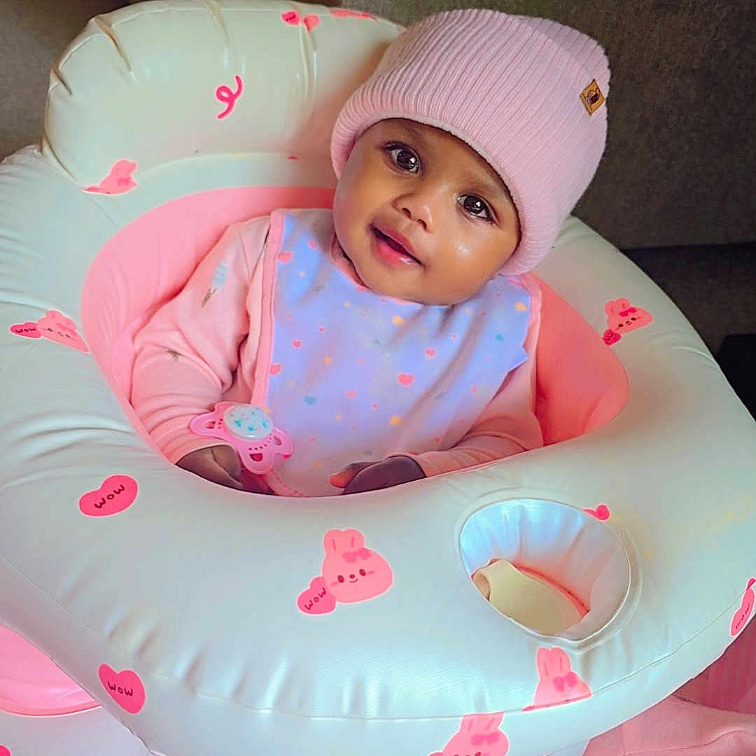Wareef joined the competition — help win amazing prizes! baby, child, infant, portrait, smiling, pink_beanie, hat, onesie, bib, toy, baby_walker, inflatable, pastel, bunny, stickers, indoor, seated, couch, carpet, happy