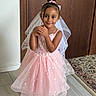 Lilyana is registered to the contest to win money with this photo: child, girl, portrait, pink_dress, princess_dress, veil, hair_bow, smiling, standing, indoors, wooden_door, tiled_floor, patterned_rug, home, fashion, dress_up, sparkles, hands_clasped, full_body, photography