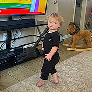 Bentley joined the competition — help win amazing prizes! toddler, child, barefoot, black_clothing, standing, rug, living_room, television, cartoon, plush_toy, rocking_toy, lion, tile_floor, door, furniture, cables, expression, hair, indoors, person