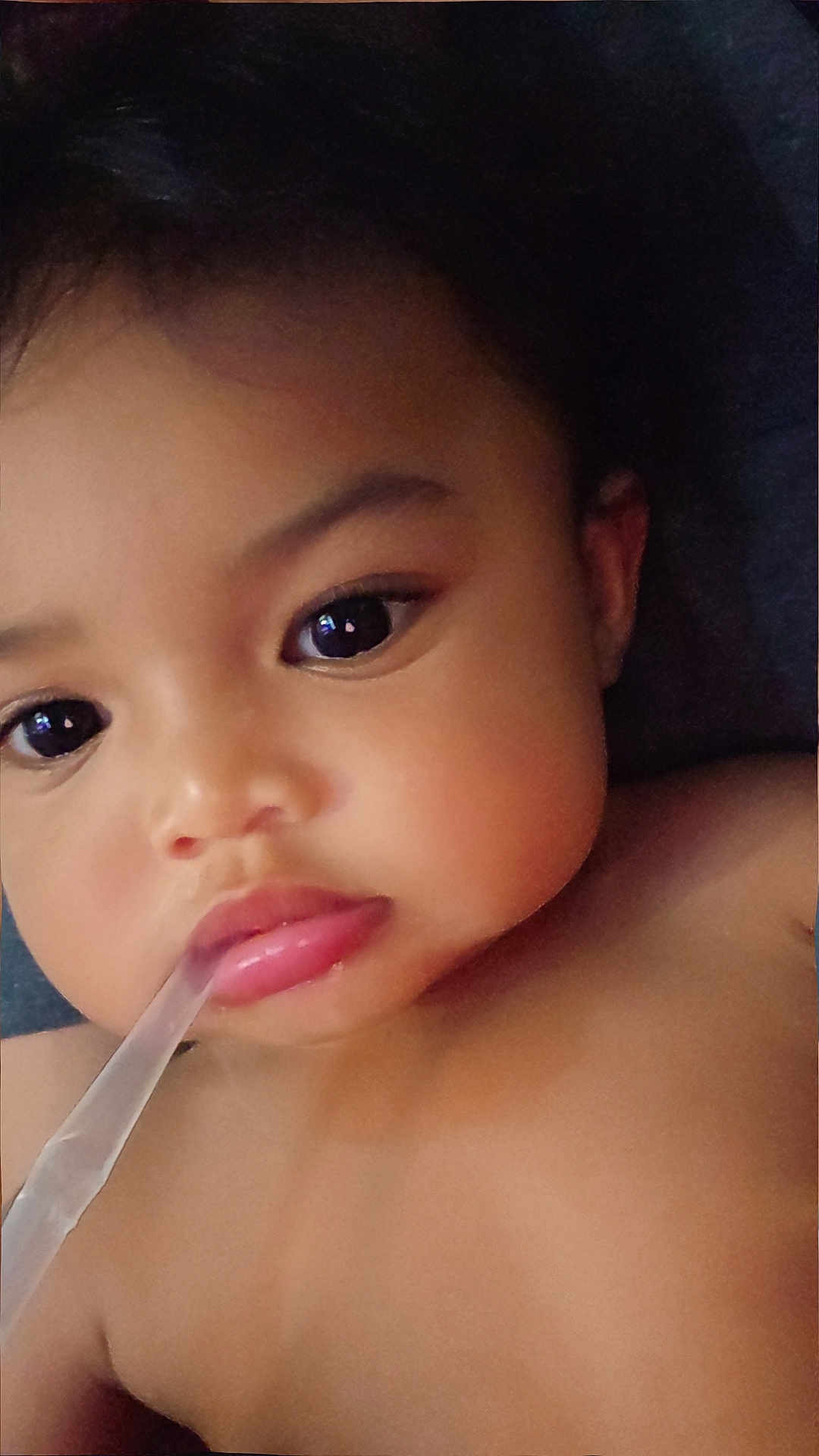 Mileena joined the competition — help win amazing prizes! baby, close_up, face, child, skin, lips, eyes, expression, curious, straw, mouth, cheeks, portrait, cute, infant, young, indoor, person, dark_background, soft_light