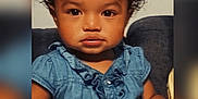 Mileena is registered to the contest to win money with this photo: arm, baby, blue_bow, child, clothing, couch, curly_hair, cute, denim_dress, expression, eyes, face, indoor, person, portrait, sitting, skin, smile, toddler, young