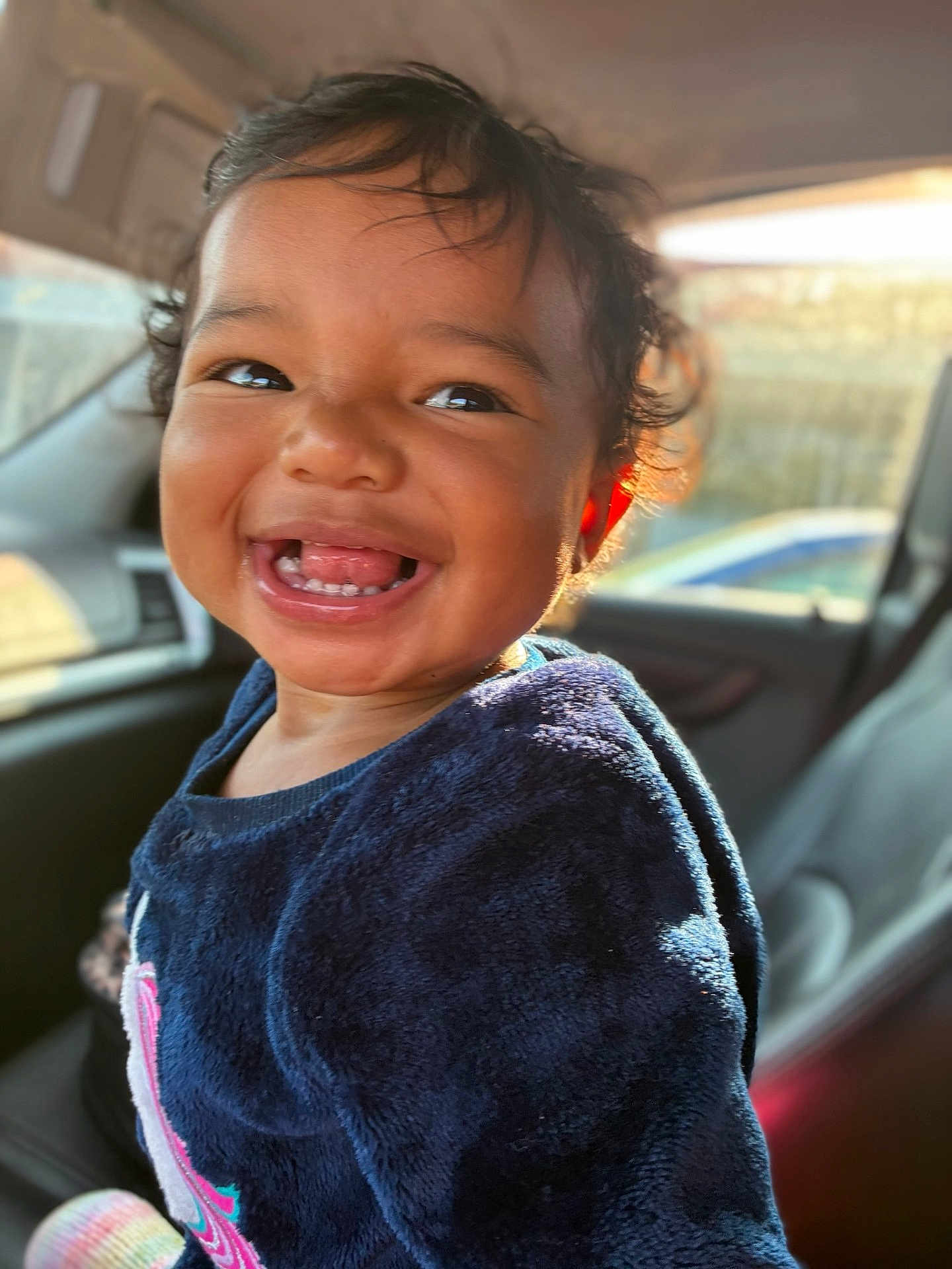 Mileena joined the competition — help win amazing prizes! toddler, child, smile, happy, face, teeth, curly_hair, blue_sweater, car_interior, window, sunlight, portrait, person, young_child, seat, clothing, indoors, cute, joyful, baby