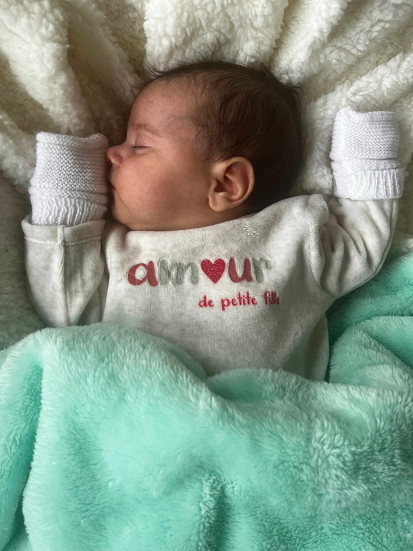 Alya participe au concours pour gagner de l'argent avec cette photo : baby, sleeping, blanket, mittens, clothing, face, infant, soft, cozy, cute, resting, warm, child, portrait, closeup, text_on_clothing, peaceful, indoors, fabric, head