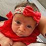 baby, infant, headband, bow, red_dress, close_up, face, eyes, hand, skin, person, cute, child, holding, indoor, soft_light, portrait, expression, young, cozy