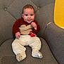 baby, child, smiling, sitting, sweater, pants, sock, chair, cushion, ornament, red, gray, cozy, cute, indoor, portrait, happy, face, hand, furniture
