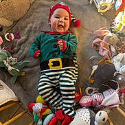 Lyson participe au concours pour gagner de l'argent avec cette photo : baby, child, smiling, elf_costume, striped_pants, red_hat, toys, stuffed_animals, blanket, happy, indoor, floor, plush, colorful, playtime, cute, infant, holiday, festive, cheerful