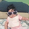 baby, infant, child, portrait, sunglasses, heart_shaped_sunglasses, pink_clothing, pajamas, sitting, bed, blanket, bedroom, indoor, patterned_bedding, dark_hair, face, fashion, cute, casual, photography