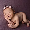 baby, newborn, sleeping, smiling, headband, flower, purple_blanket, skin, infant, cute, peaceful, lying_down, hand_near_face, portrait, soft_texture, closed_eyes, adorable, child, resting, small