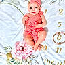 baby, infant, smiling, headband, pink_clothing, milestone_blanket, floral_pattern, number_8, months, cute, happy, lying_down, portrait, child, skin, blue_eyes, small_hands, small_feet, indoors, colorful