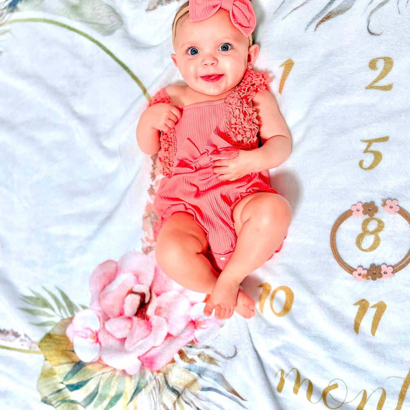 Lyana is registered to the contest to win money with this photo: baby, infant, smiling, headband, pink_clothing, milestone_blanket, floral_pattern, number_8, months, cute, happy, lying_down, portrait, child, skin, blue_eyes, small_hands, small_feet, indoors, colorful