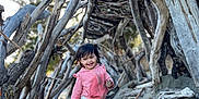 Judah joined the competition — help win amazing prizes! child, toddler, smiling, pink_hoodie, camo_pants, barefoot, sand, beach, driftwood, wood_structure, outdoor, nature, sunlight, playful, happy, portrait, tree_branches, daylight, person, fun