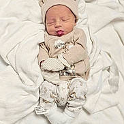 Braxton joined the competition — help win amazing prizes! newborn, baby, infant, sleeping, hat, mittens, onesie, cute, cozy, blanket, soft, puckered_lips, lying_down, clothing, white, beige, face, headwear, footwear, indoors