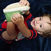 Atticus joined the competition — help win amazing prizes! toddler, child, baby, smiling, shoe, hand, face, hair, blanket, clothing, striped, cute, playful, lying_down, indoors, portrait, happy, skin, footwear, person
