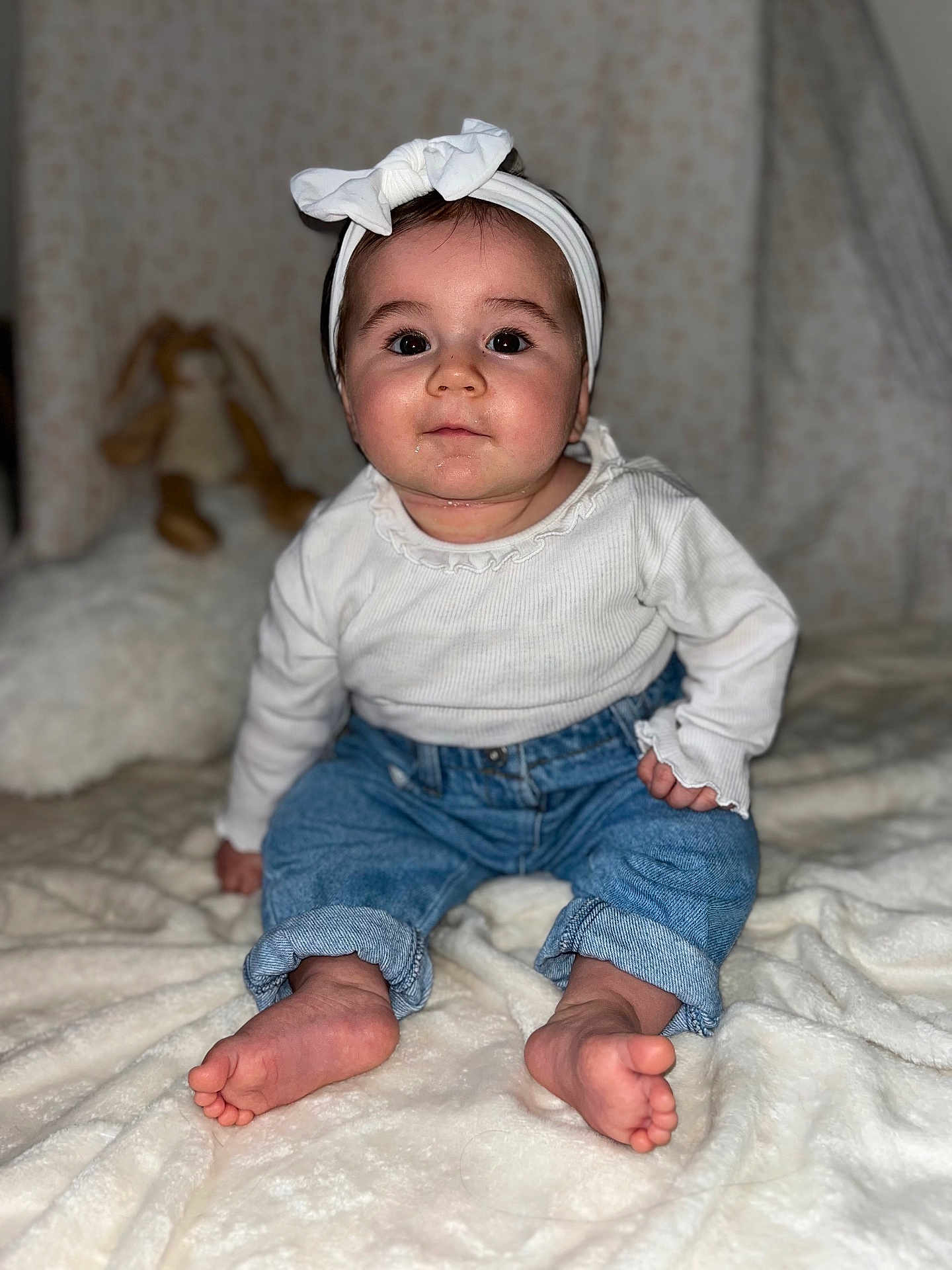 Valentina participe au concours pour gagner de l'argent avec cette photo : baby, child, headband, white_top, blue_jeans, barefoot, sitting, blanket, plush_toy, bunny, indoor, face, portrait, cute, infant, soft_texture, cozy, warm_lighting, curious, young_child
