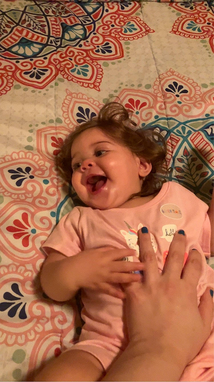 Kylee is registered to the contest to win money with this photo: baby, cheek, child, chin, eye, face, finger, foot, fun, gesture, happy, head, linens, mouth, person, pink, skin, smile, t_shirt, thumb