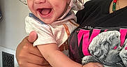 Mateo joined the competition — help win amazing prizes! baby, child, smiling, laughing, hat, dinosaur_print, shorts, tshirt, adult_hand, beaded_necklace, indoor, laundry_basket, clothes, happy, person, holding, cute, face, portrait, home