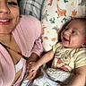 woman, baby, smile, holding_hands, bed, pillow, blanket, winnie_the_pooh, clothing, face, happy, indoor, person, cute, pattern, dinosaur, cactus, pink_robe, baby_boy, family