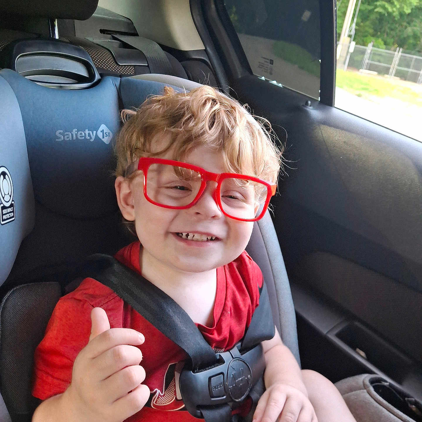Waylon joined the competition — help win amazing prizes! child, toddler, car_seat, red_glasses, safety, smiling, thumbs_up, blonde_hair, seatbelt, car_interior, window, casual_clothing, happy, portrait, child_safety, candid, daylight, cute, young_child, car_trip