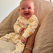 Ella joined the competition — help win amazing prizes! baby, smiling, infant, onesie, patterned_clothing, happy, human_arm, skin, indoor, couch, fabric, beige, portrait, cute, child, person, sitting, hand, warm, cozy