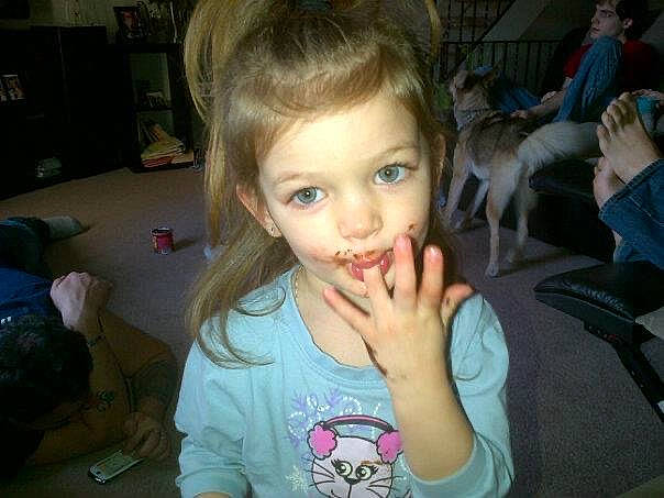 Faythe is registered to the contest to win money with this photo: blond, chair, cheek, child, ear, eyelash, fun, gesture, hairstyle, happy, iris, jaw, mouth, nose, person, shelf, skin, smile, t_shirt, thumb