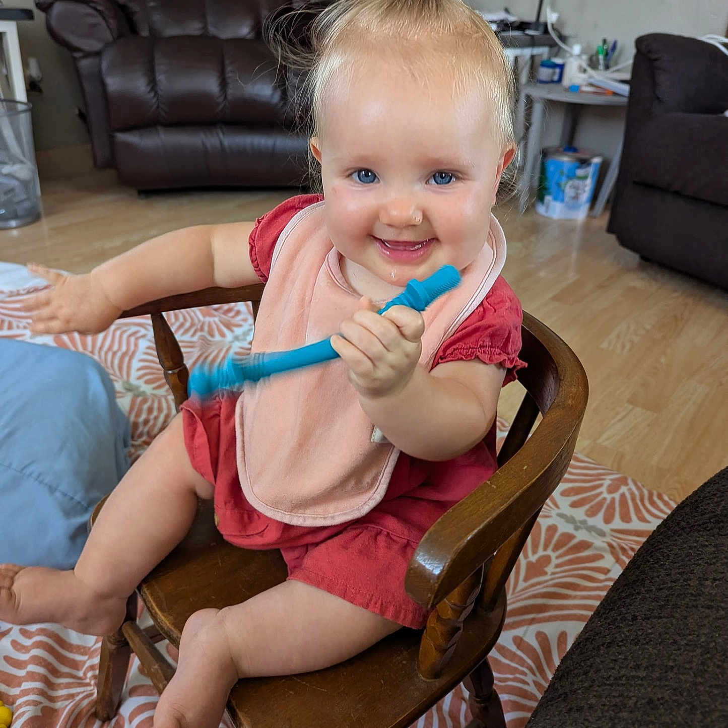 Emmilynn joined the competition — help win amazing prizes! baby, blue_eyes, carpet, child, cute, flooring, furniture, hair_tie, happy, indoor, lamp, living_room, person, pink_bib, red_dress, smiling, table, toddler, toy, wooden_chair