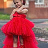 brick_wall, child, cute, dress, earrings, fashion, feet, girl, happy, headband, outdoor, portrait, posing, red_dress, ribbons, smile, socks, street, tulle, young