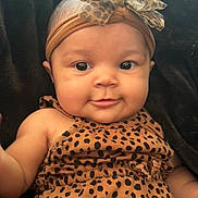 Serenity joined the competition — help win amazing prizes! baby, infant, child, face, headband, bow, leopard_print, clothing, cute, smile, portrait, skin, eyes, cheeks, sitting, indoors, black_background, fashion, headwear, person