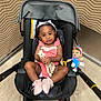 Xena joined the competition — help win amazing prizes! toddler, child, stroller, pink_outfit, pink_shoes, giraffe_toy, plush_doll, indoor, floor, wall, black_stroller, happy, smiling, headband, toy, person, seated, cute, baby, playful