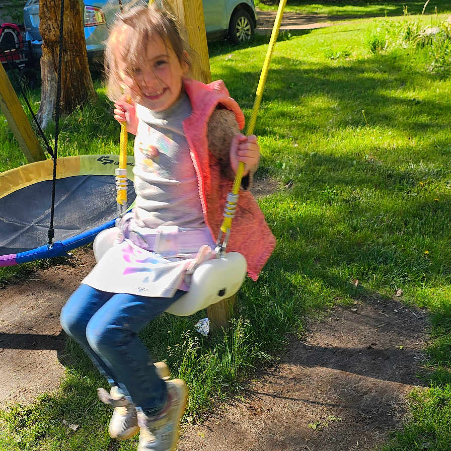 Alexandria is registered to the contest to win money with this photo: car, child, clothing, daylight, footwear, fun, grass, happy, house, motion_blur, nature, outdoor, person, play, playground, rope, smiling, swing, tree, wood