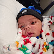 Jamari is registered to the contest to win money with this photo: baby, infant, blanket, beanie, nike, hat, face, closeup, pillow, cozy, soft, colorful, cute, child, young, indoors, portrait, warm, resting, clothing