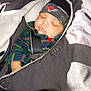 Jamari is registered to the contest to win money with this photo: baby, sleeping, blanket, headband, nike, camo, clothing, infant, child, car_seat, seatbelt, peaceful, cozy, red_sleeve, plaid_shirt, warm, indoors, portrait, cute, resting