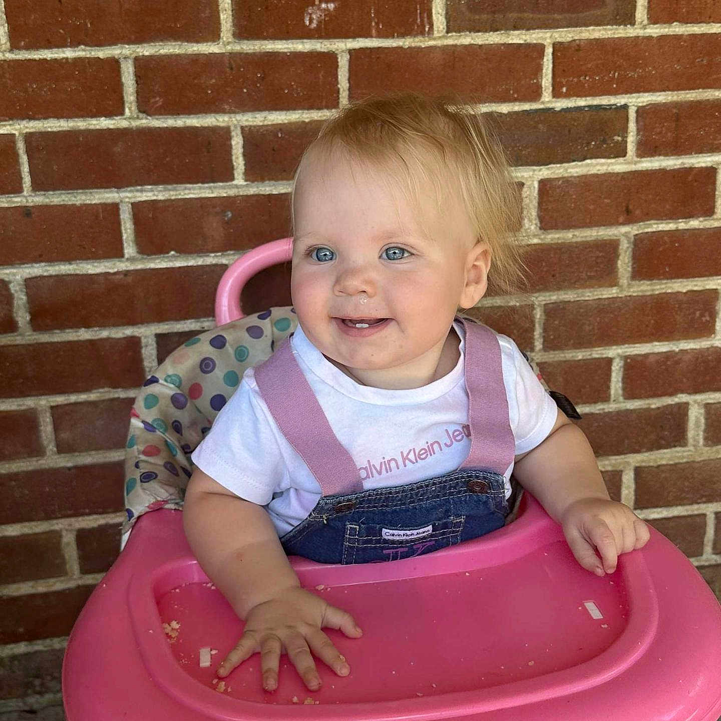 Harper is registered to the contest to win money with this photo: baby, brick, chair, city, clothing, face, furniture, happy, head, pants, person, photography, plant, portrait, pottedplant, road, sitting, smile, street, t_shirt