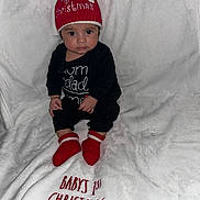 Elias joined the competition — help win amazing prizes! baby, infant, red_hat, christmas, holiday, blanket, red_booties, black_clothing, sitting, cute, festive, indoors, portrait, child, winter_wear, soft_texture, cozy, face, expression, celebration