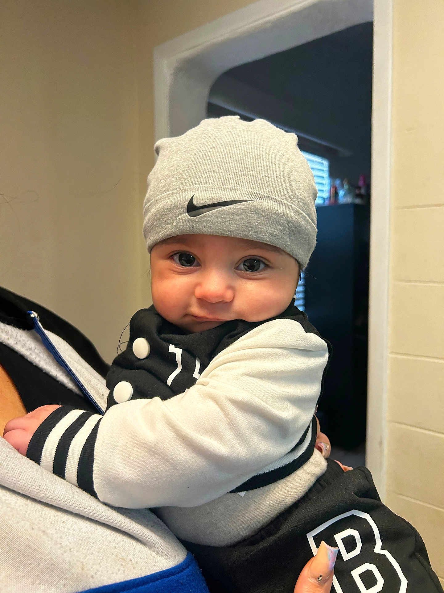 Elias joined the competition — help win amazing prizes! baby, child, beanie, hat, clothing, jacket, person, indoor, closeup, face, eyes, hand, holding, cute, adorable, portrait, infant, black_and_white, nike, warm
