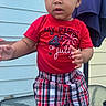 Azrael Young joined the competition — help win amazing prizes! child, toddler, baby, standing, portrait, red_hat, red_shirt, plaid_shorts, red_shoes, patriotic_clothing, fourth_of_july, outdoor, patio, glass_table, house, siding, lantern, curtain, fashion, smiling