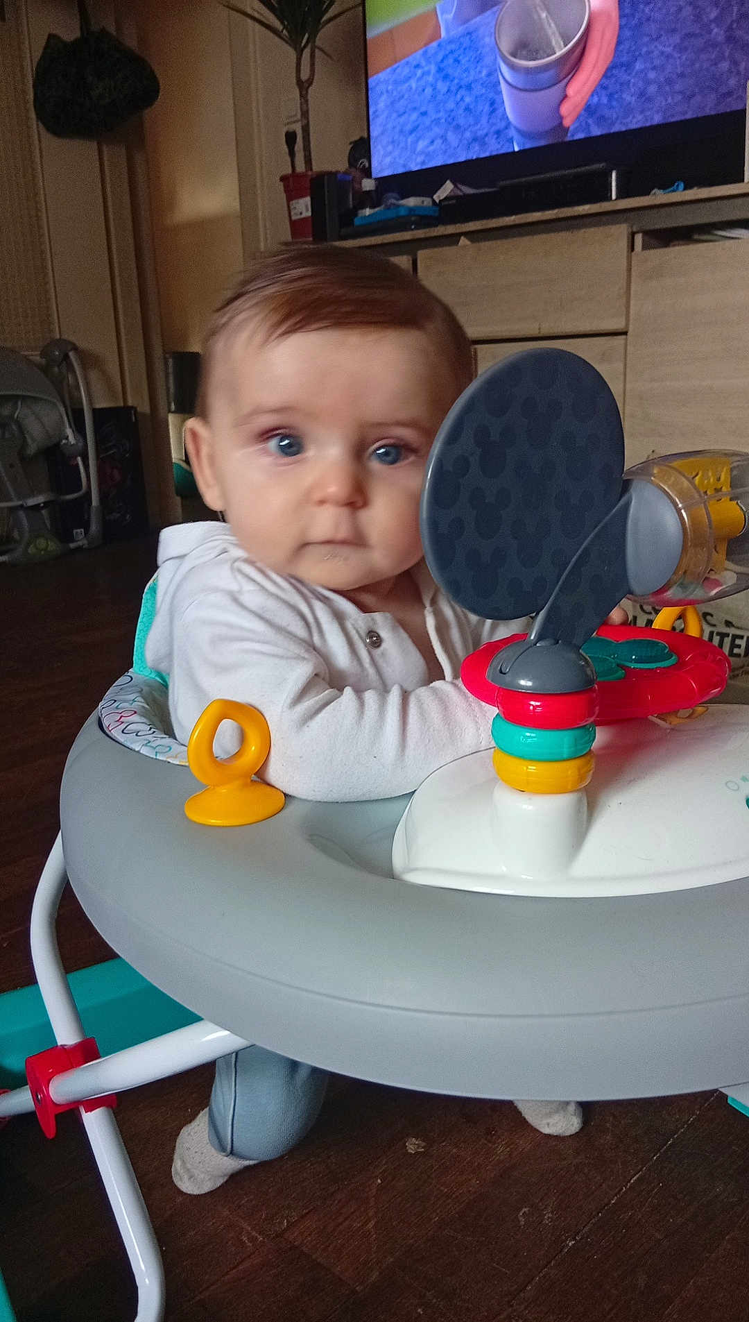 Naël participe au concours pour gagner de l'argent avec cette photo : baby, blue_eyes, baby_walker, toy, indoor, child, person, floor, furniture, clothing, socks, face, hair, living_room, television, cabinet, wood_floor, curious, seated, home