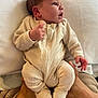 newborn, baby, infant, onesie, clothing, hands, face, adult_hands, blanket, soft_texture, indoor, portrait, cute, curious, cozy, human, skin, sleepwear, newborn_clothing, baby_onesie