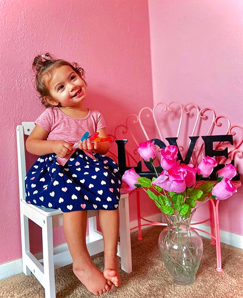 Fraya is registered to the contest to win money with this photo: baby_toddler_clothing, bouquet, chair, child, design, dress, flower, footwear, furniture, joy, pattern, person, pink, plant, play, polka_dot, room, shoe, sitting, toddler