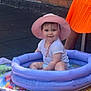 River joined the competition — help win amazing prizes! baby, child, inflatable_pool, pink_hat, white_shirt, towel, outdoor, brick_wall, colorful, smiling, sitting, summer, play, sunhat, legs, person, water, fun, cute, orange_skirt