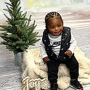 Amir joined the competition — help win amazing prizes! baby, child, portrait, christmas, holiday, christmas_tree, festive, smiling, sitting, indoors, fashion, nike, vest, sneakers, black_clothing, white_shirt, fluffy_rug, wooden_sign, joy, potted_tree
